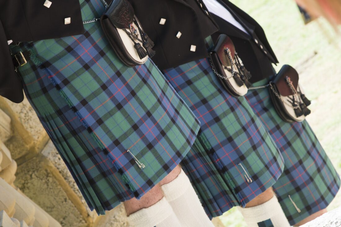 A,Closeup,Of,Three,Men's,Legs,In,Scottish,Kilt,Standing