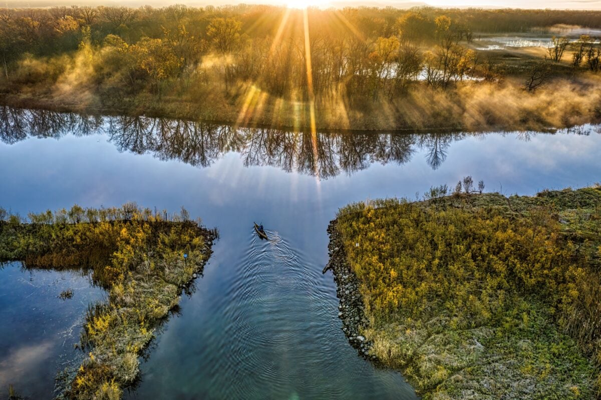 Aerial view of sunrise over wetland with sunrays and water reflection. Perfect for nature and travel themes.