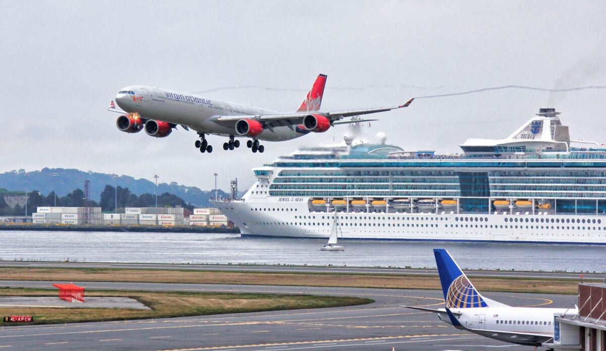 A thrilling view of an airplane landing with a cruise ship passing by in Boston Harbor.