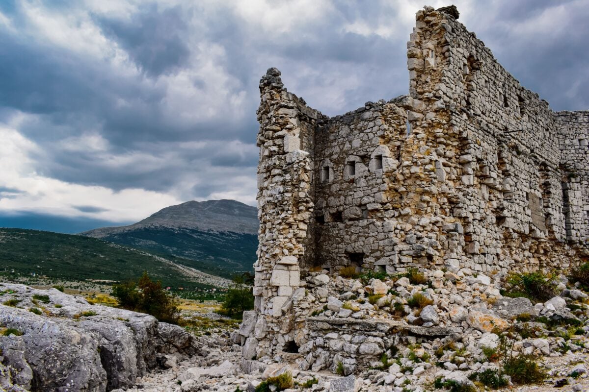 Explore the rugged charm of ancient stone ruins against the dramatic Bosnian mountains.