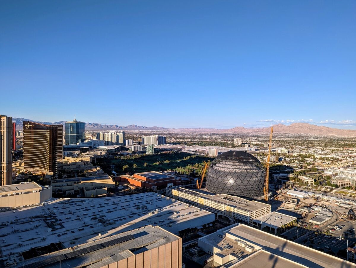 A breathtaking aerial view of Las Vegas with a prominent sphere-shaped landmark and clear blue skies.