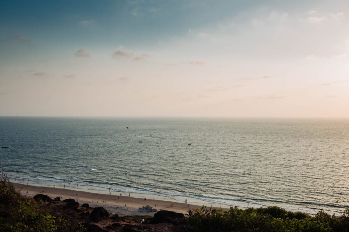 A tranquil view of Chapora Beach in Goa, India captured during sunset with gentle waves and a serene sky.