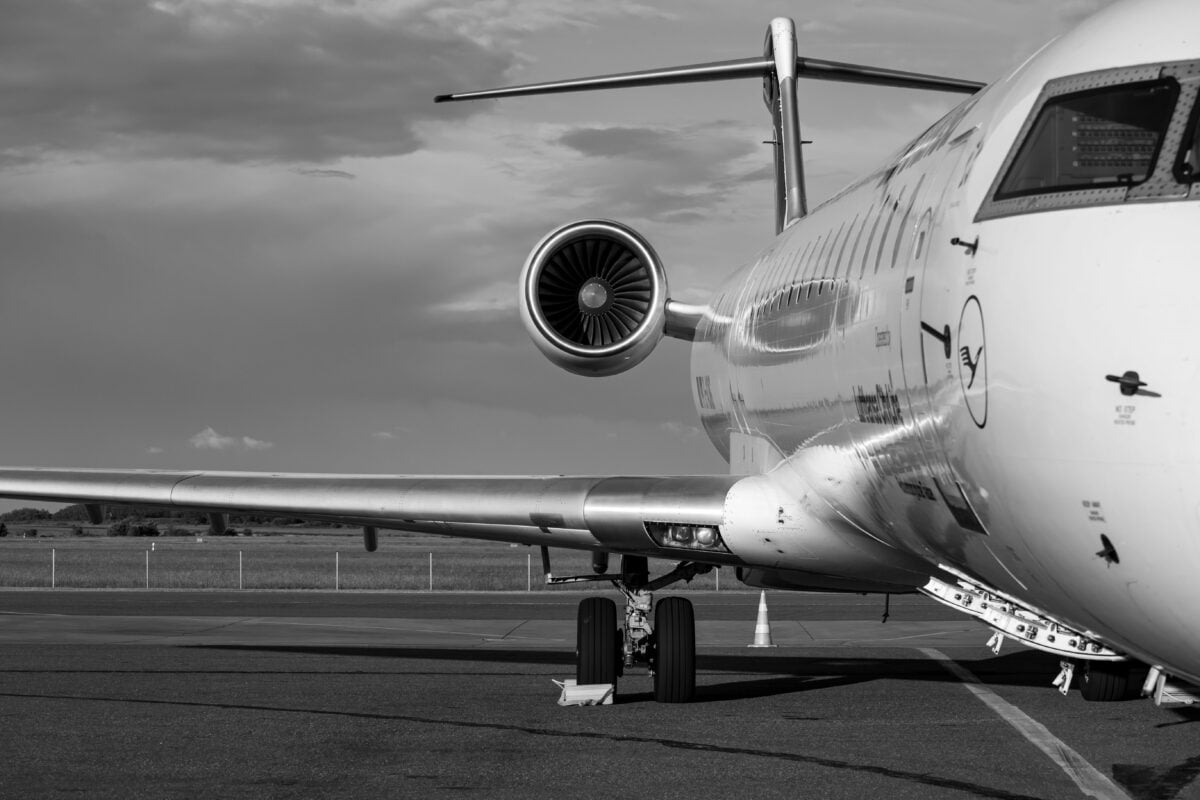 Monochrome photo of a commercial jet airplane taken from the side at an airport.
