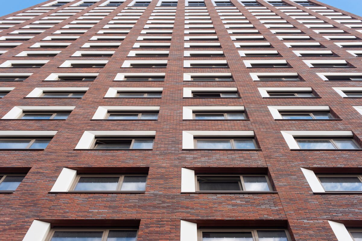 pexels 32238931 | Two Scots Abroad Upward view of a tall brick building facade with uniform windows against a clear sky.