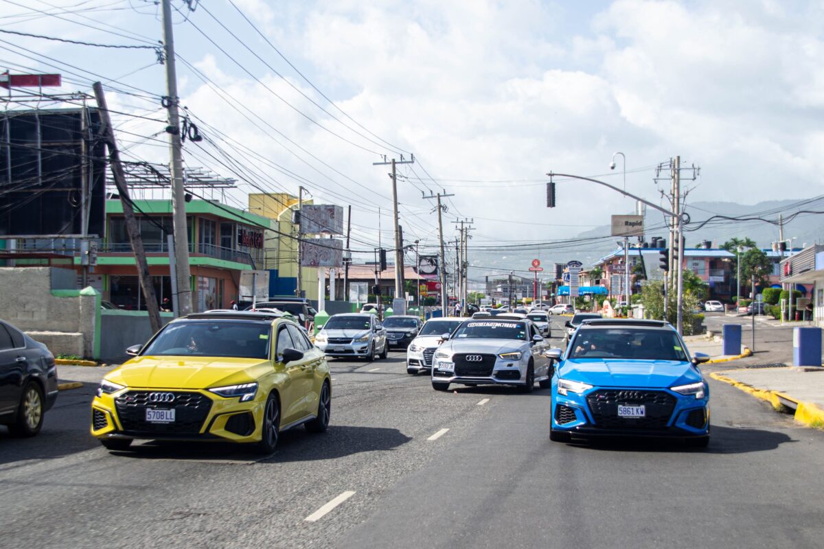 Dynamic street scene in Jamaica featuring colorful cars driving through a vibrant urban area.