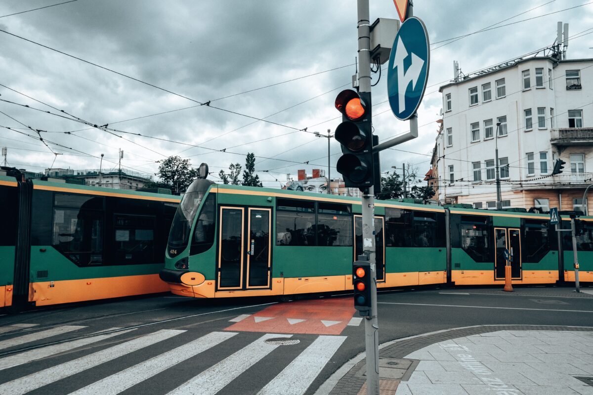 pexels 12476870 | Two Scots Abroad Green and yellow trams at a city intersection in Poznań, capturing urban transportation.