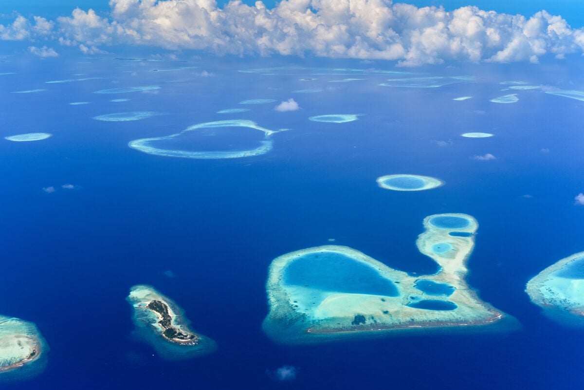 pexels 12858510 | Two Scots Abroad Breathtaking aerial view of turquoise atolls surrounded by deep blue ocean under a vibrant sky.