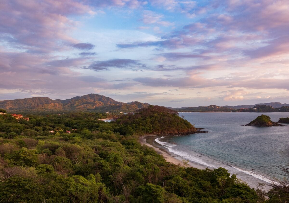 pexels 15365639 | Two Scots Abroad A stunning aerial view of the Guanacaste coastline at sunset with lush greenery and gentle waves.