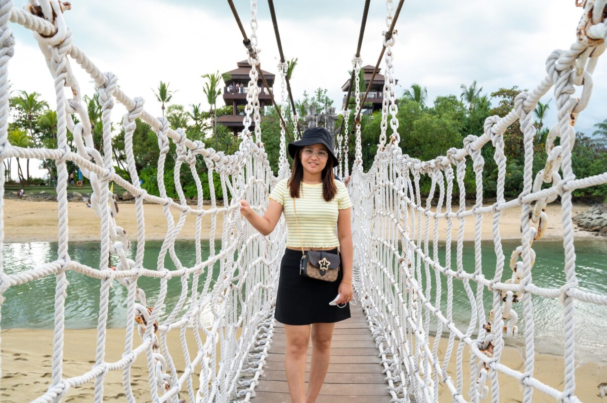 Woman enjoying a walk on a suspension bridge at Sentosa Island, Singapore on a sunny day.