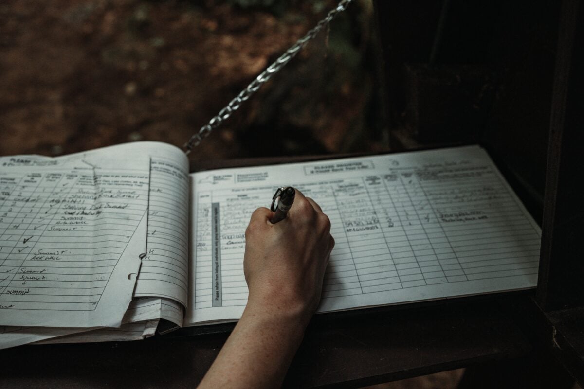 pexels 17616803 | Two Scots Abroad Close-up of a person writing in an outdoor logbook on a table.