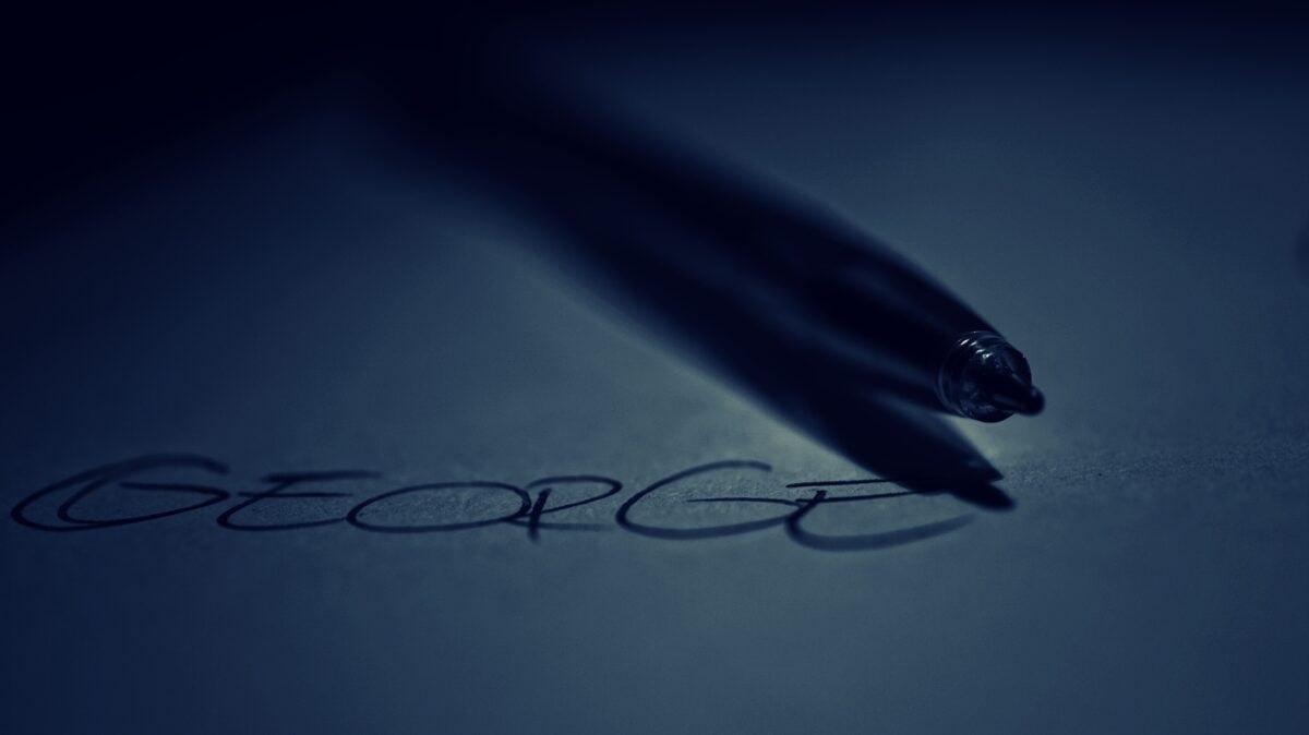pexels 243338 | Two Scots Abroad A dark, moody image of a pen casting a shadow over writing on paper reading 'GEORGE'.