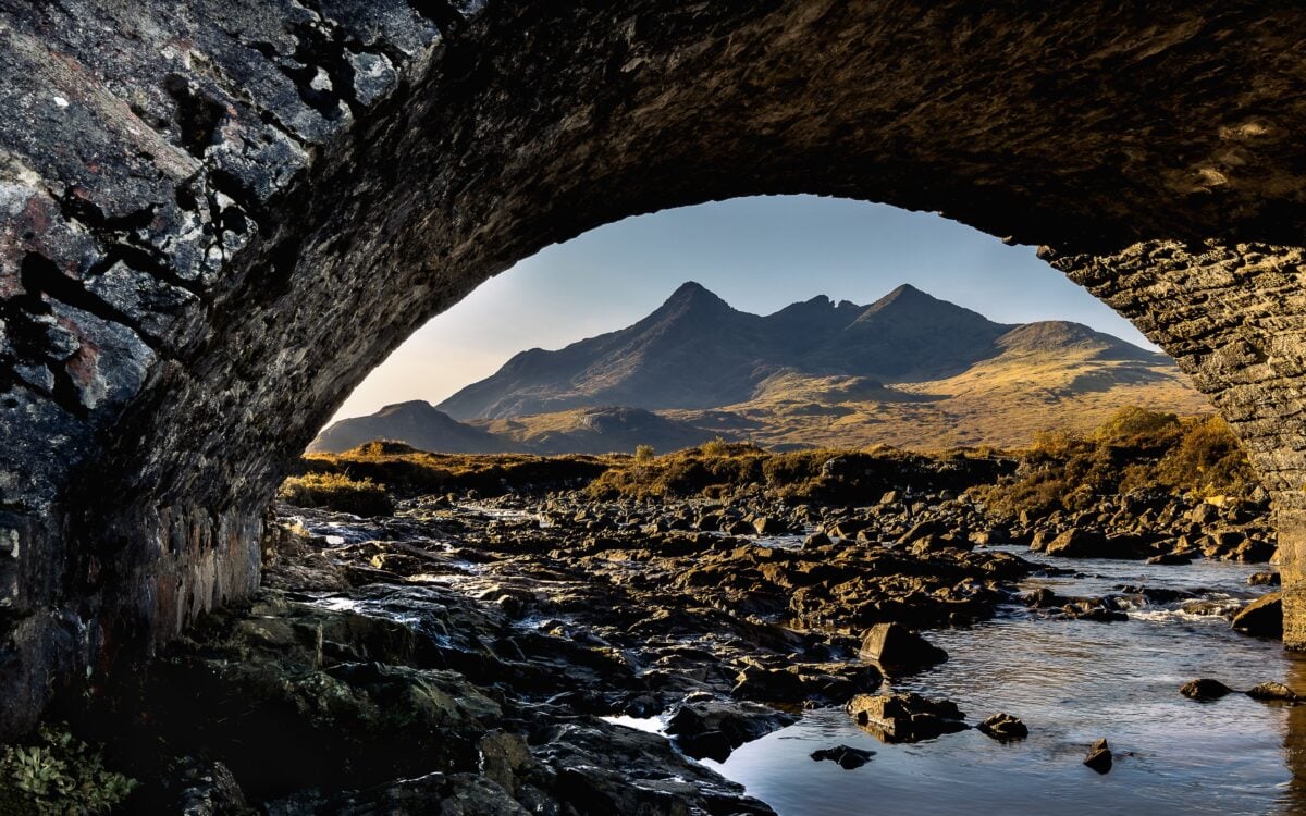 Breathtaking view of mountains through Sligachan Bridge in Scotland, capturing nature's beauty.