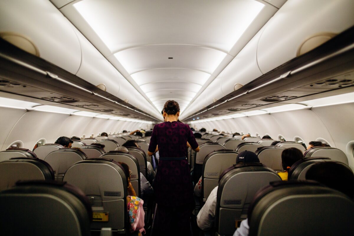 pexels 3119978 | Two Scots Abroad Interior view of an airplane cabin with passengers seated and a flight attendant walking down the aisle.