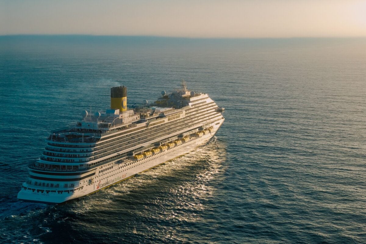 pexels 32609062 | Two Scots Abroad A breathtaking view of a cruise ship sailing across the ocean with the sun setting in the background.