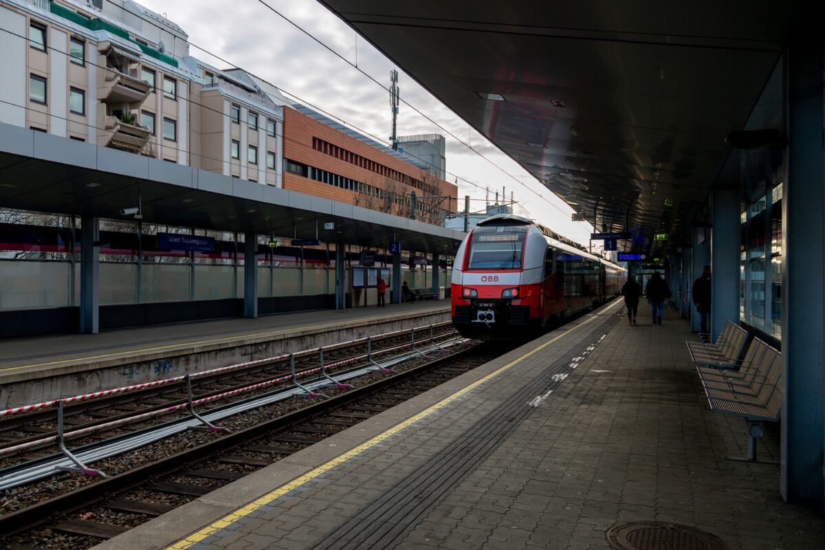 Train arriving at Vienna station on a cloudy day, capturing urban life and travel themes.
