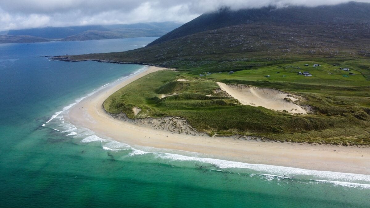 Stunning aerial view of Luskentyre Beach with turquoise waters and lush green hills in Scotland.