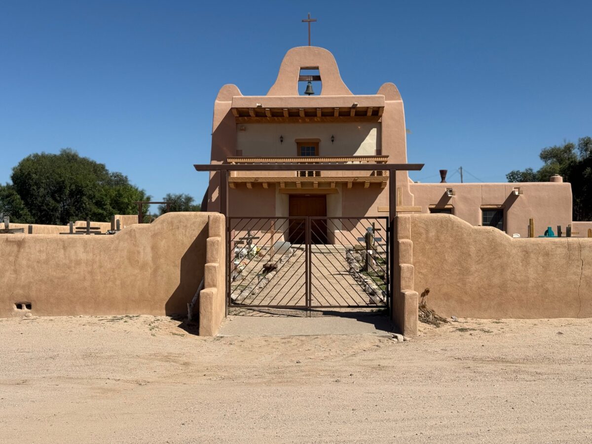 A classic adobe church with a bell tower under a clear blue sky, showcasing traditional architecture.