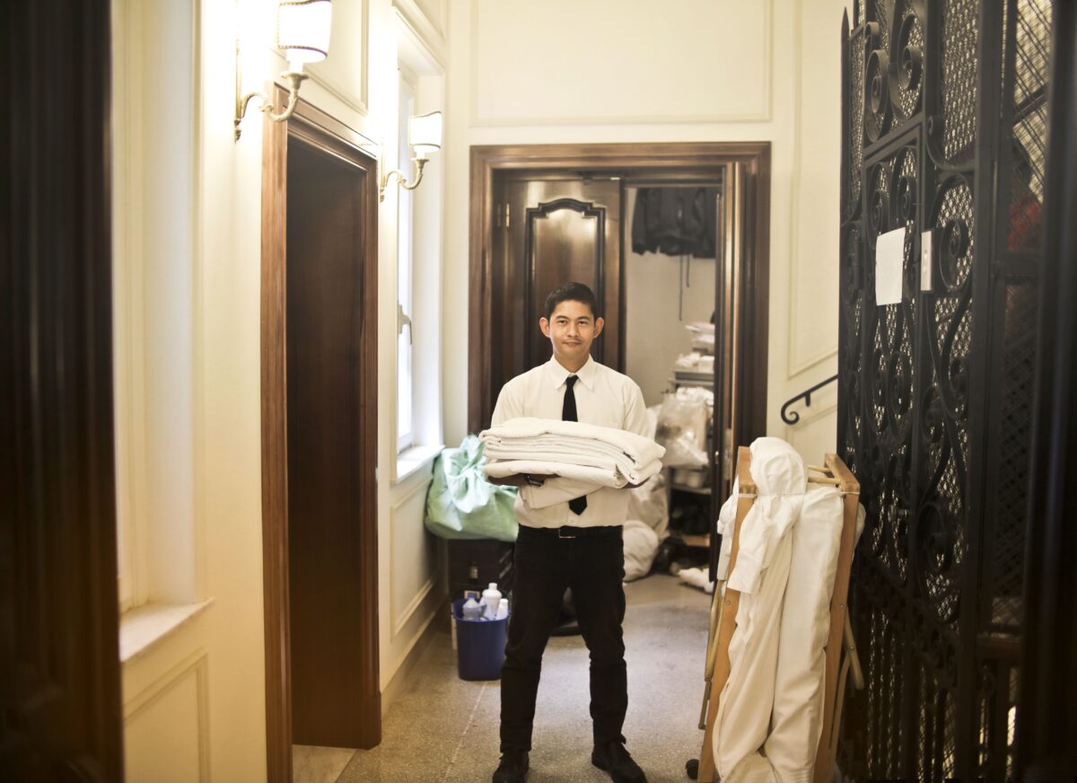 pexels 3772615 | Two Scots Abroad Professional hotel staff member carrying fresh linens in an elegant hallway.