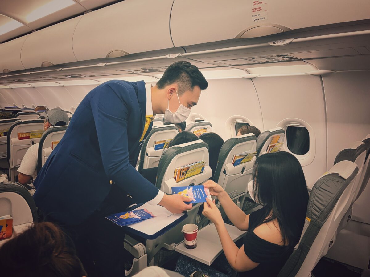 pexels 38126942 | Two Scots Abroad Flight attendant in mask serving passengers on an airplane, ensuring safety and comfort.