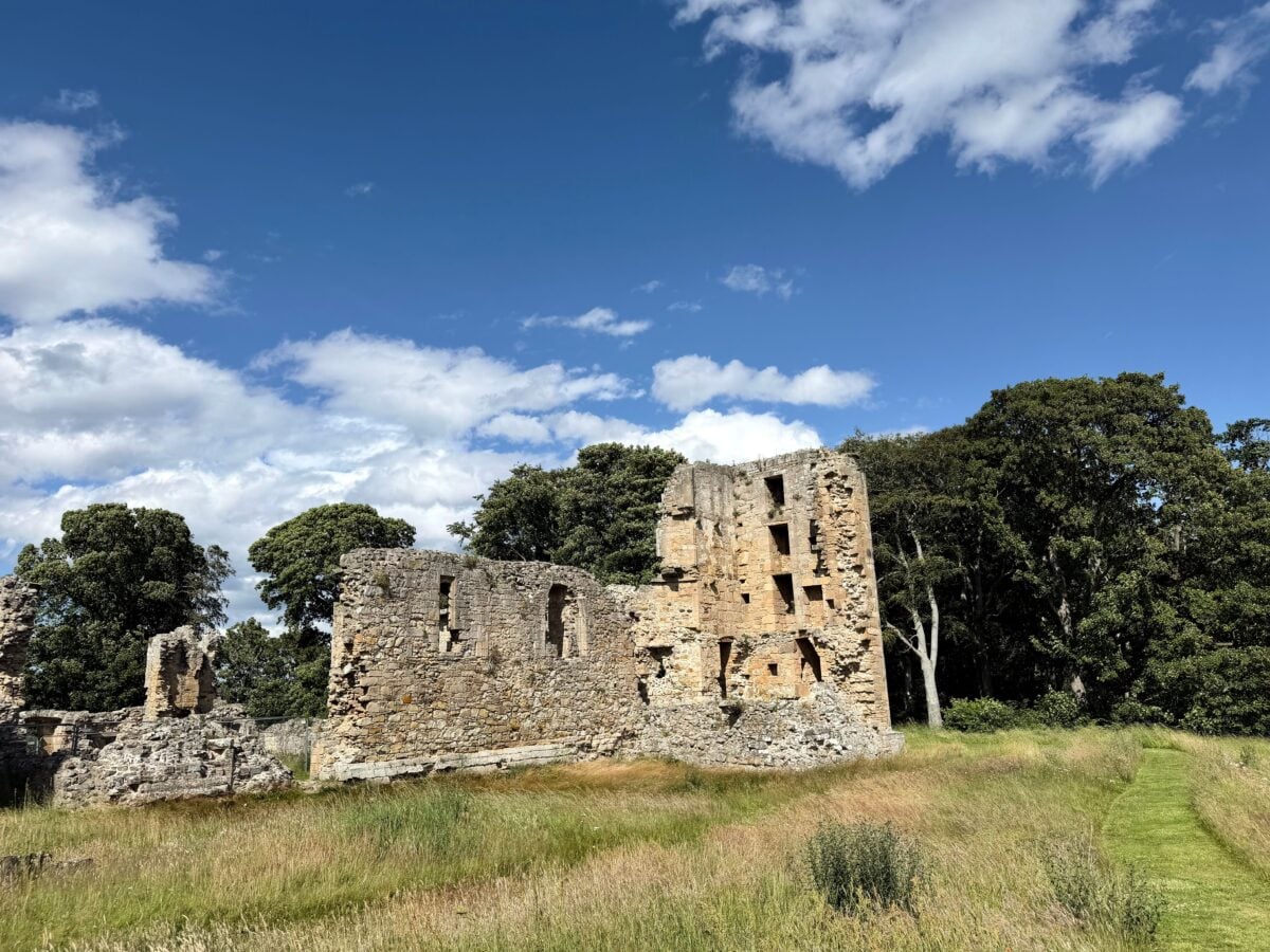 pexels 38335144 | Two Scots Abroad Historic ruins of Duffus Castle surrounded by lush greenery under a bright blue sky.