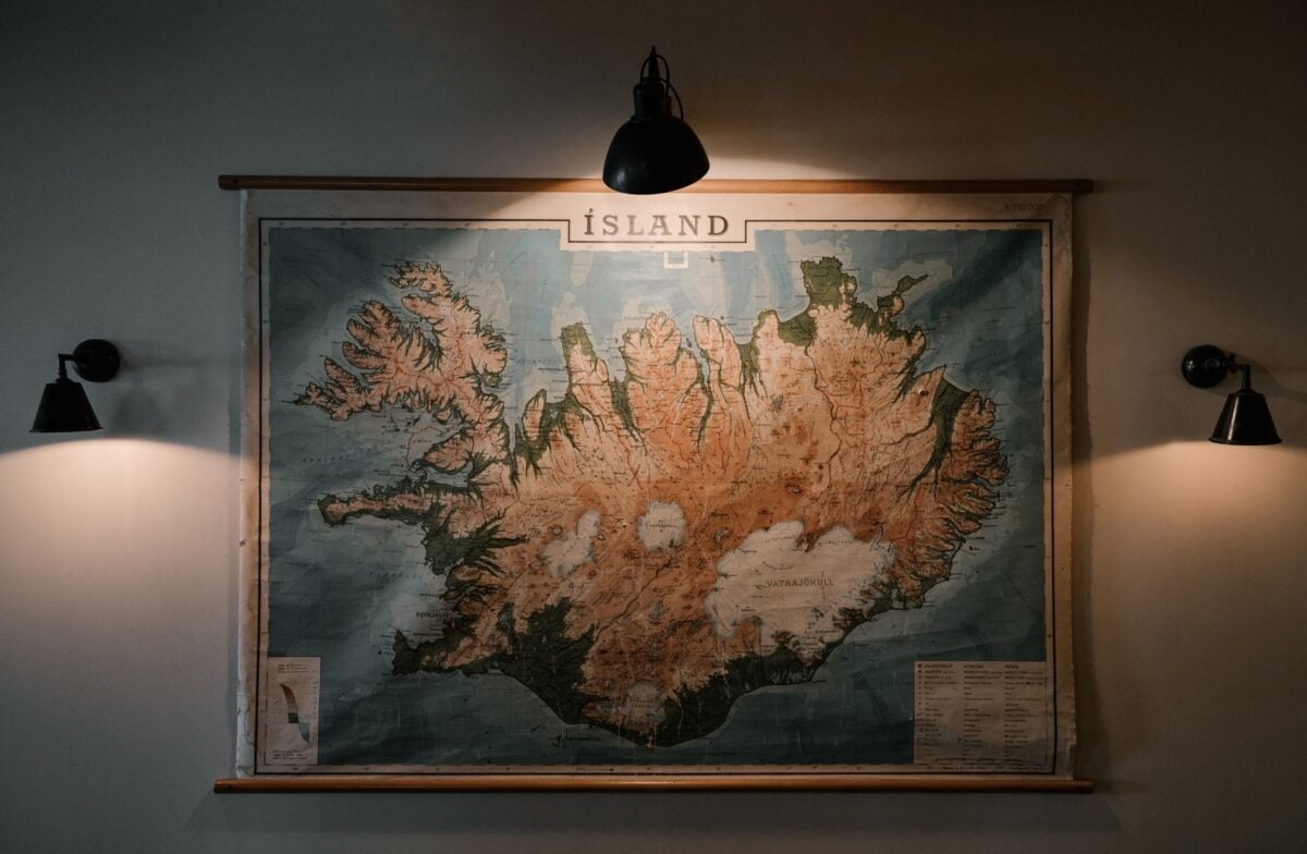Shabby looking paper map of Iceland hung on wall and lit up with small lamps in darkened room of research station