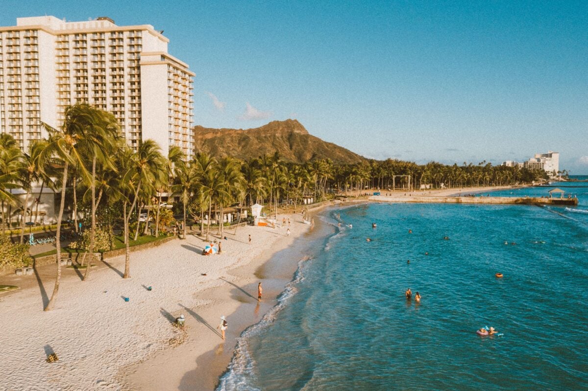 Explore the beauty of Waikiki Beach, Honolulu with palm trees and Diamond Head in the background.