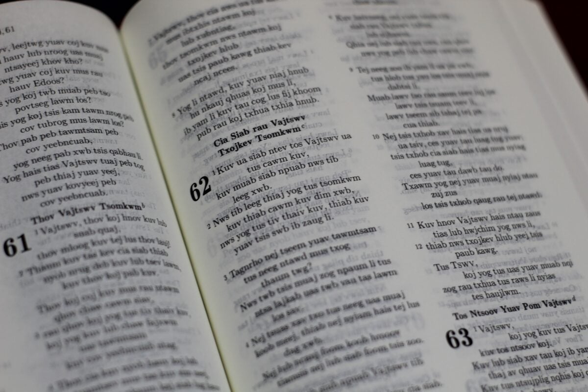 Close-up photo of an open book displaying scriptures in a unique language.