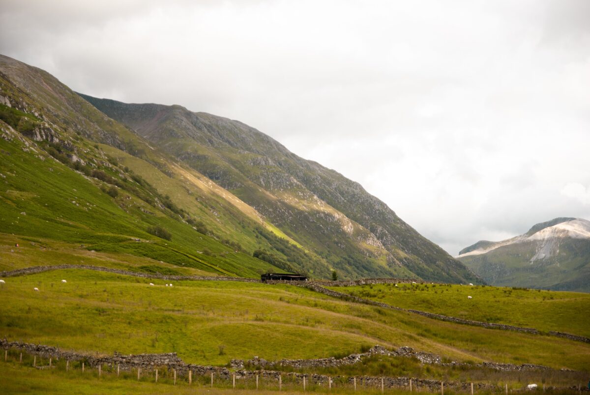 Breathtaking view of the Scottish Highlands with verdant hills and a rustic stone fence.