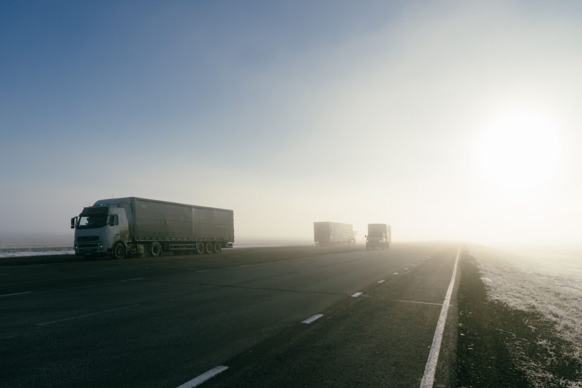 pexels 8360517 | Two Scots Abroad Freight trucks on a foggy road during sunrise, showcasing transportation in misty conditions.