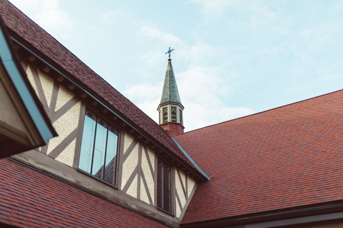 Close-up view of a church steeple with timbered architecture against a clear sky.