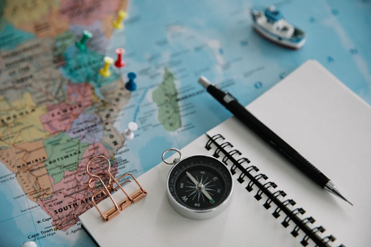 pexels 8828439 | Two Scots Abroad Flat lay of travel planning tools including a map, compass, notebook, and pen.