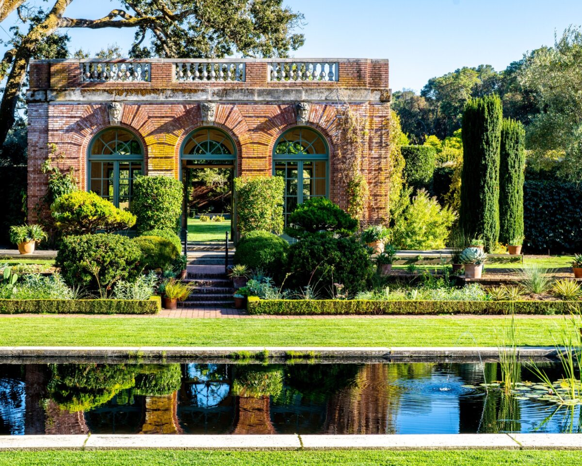 A beautiful garden with brick archways reflecting in a serene pond, set in Woodside, CA.