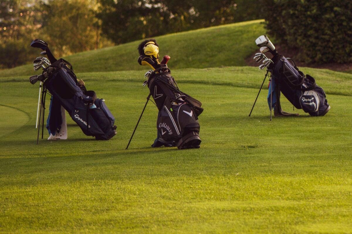 Set of golf bags on a sunlit golf course ready for a game.