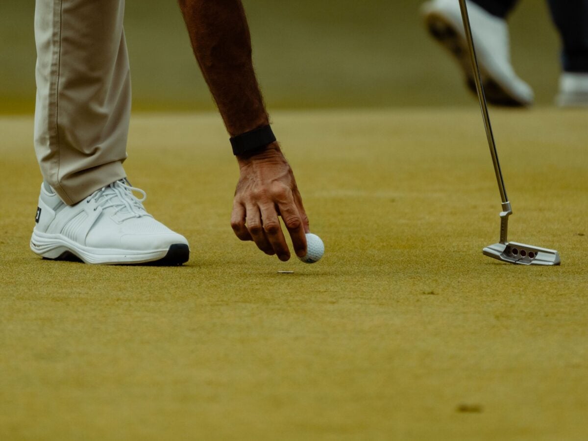 pexels 32031151 | Two Scots Abroad A golfer's hand placing a golf ball with a putter on the green.