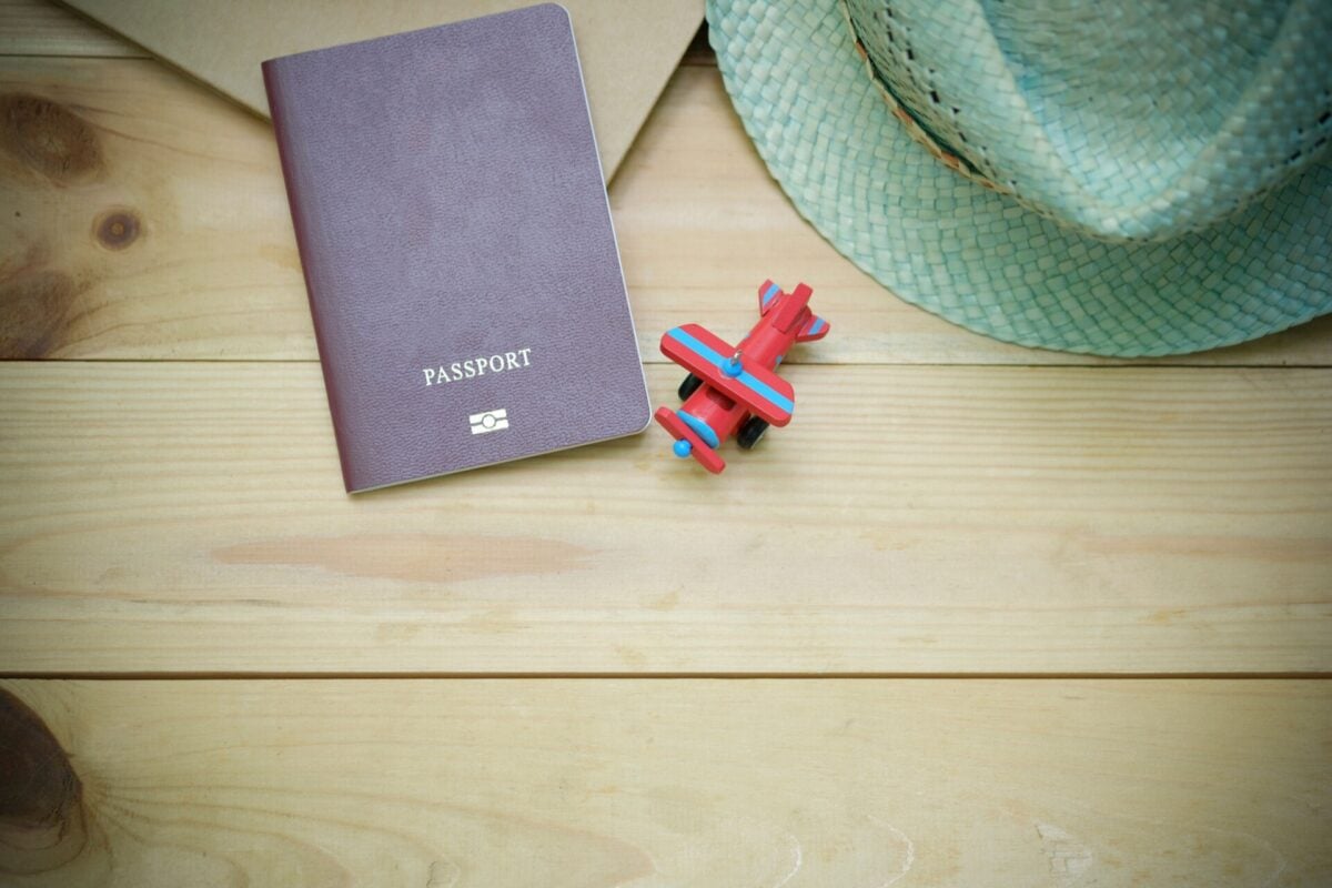 pexels 346798 | Two Scots Abroad Flat lay of a passport, straw hat, and toy airplane on a wooden surface.
