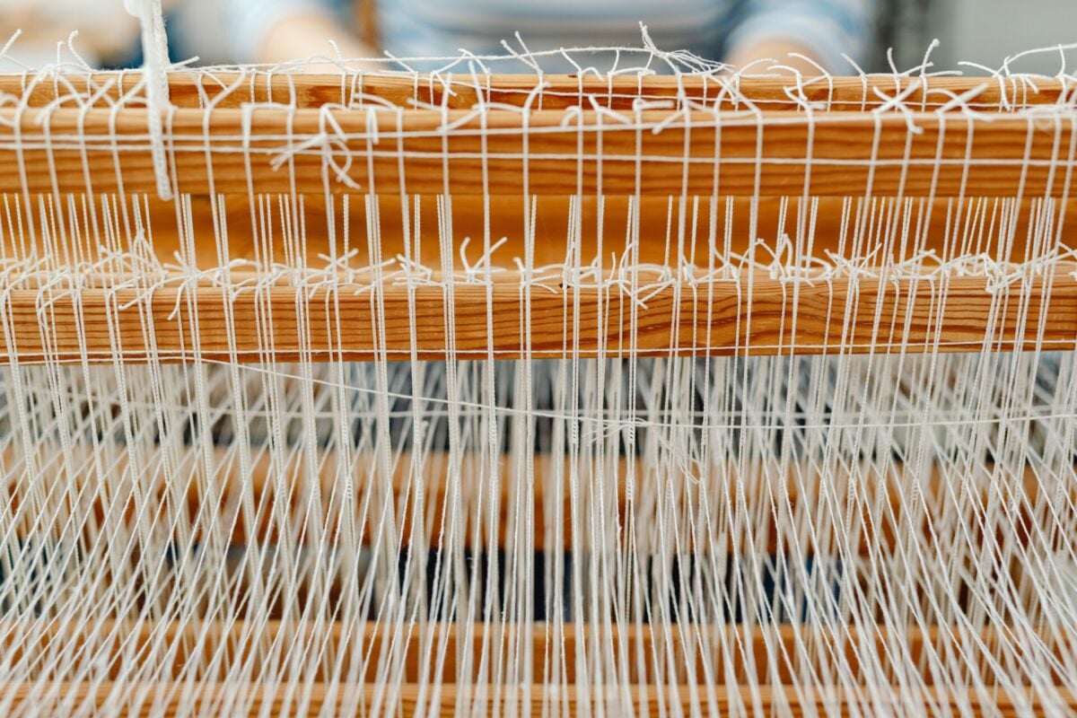 pexels 6634601 | Two Scots Abroad Detailed close-up of a wooden loom with white threads, showcasing traditional weaving.