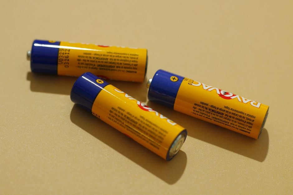 Three AA alkaline batteries on a beige surface, representing power and energy storage.