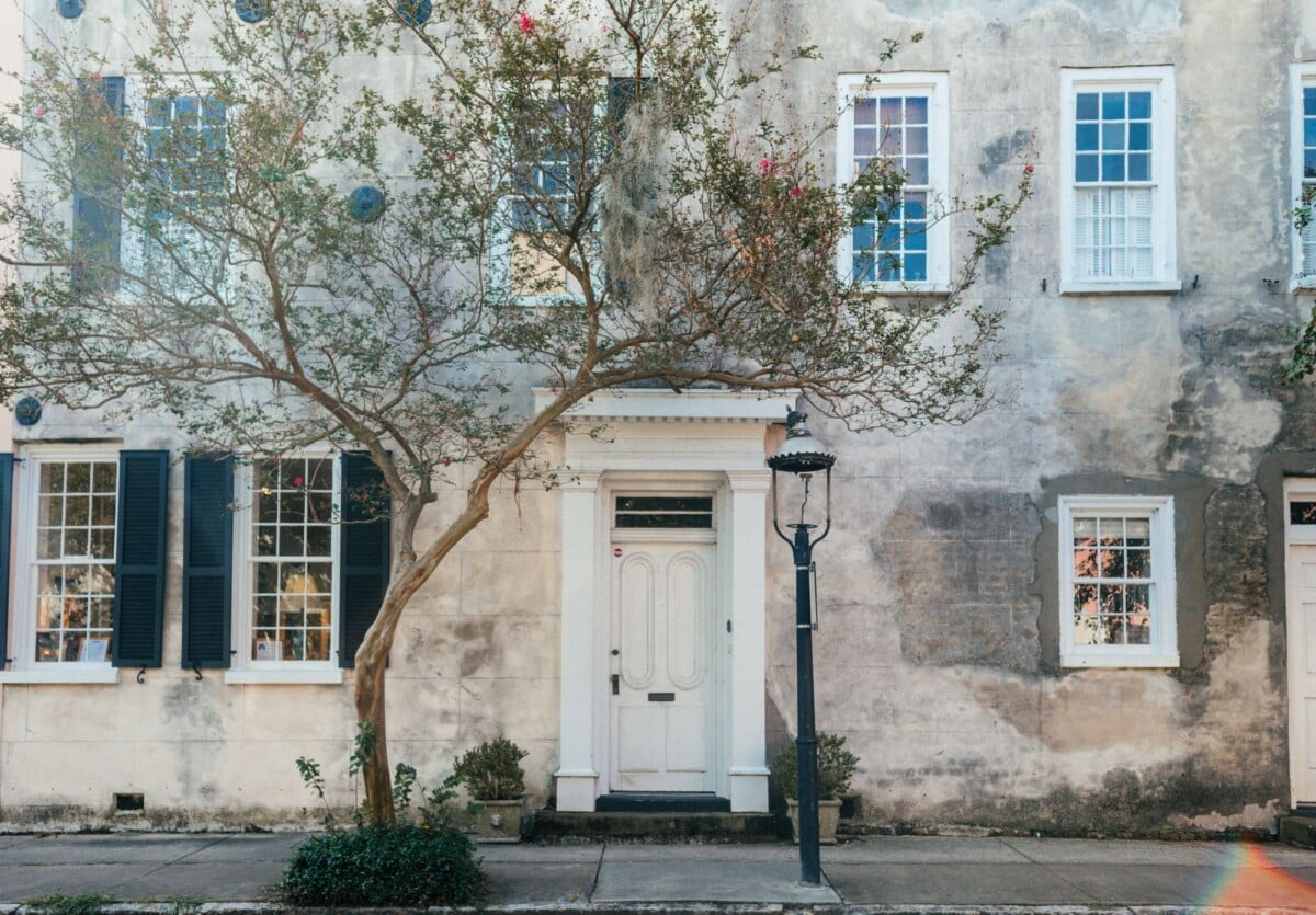 A beautiful historic house facade with lush tree and classic architecture features.