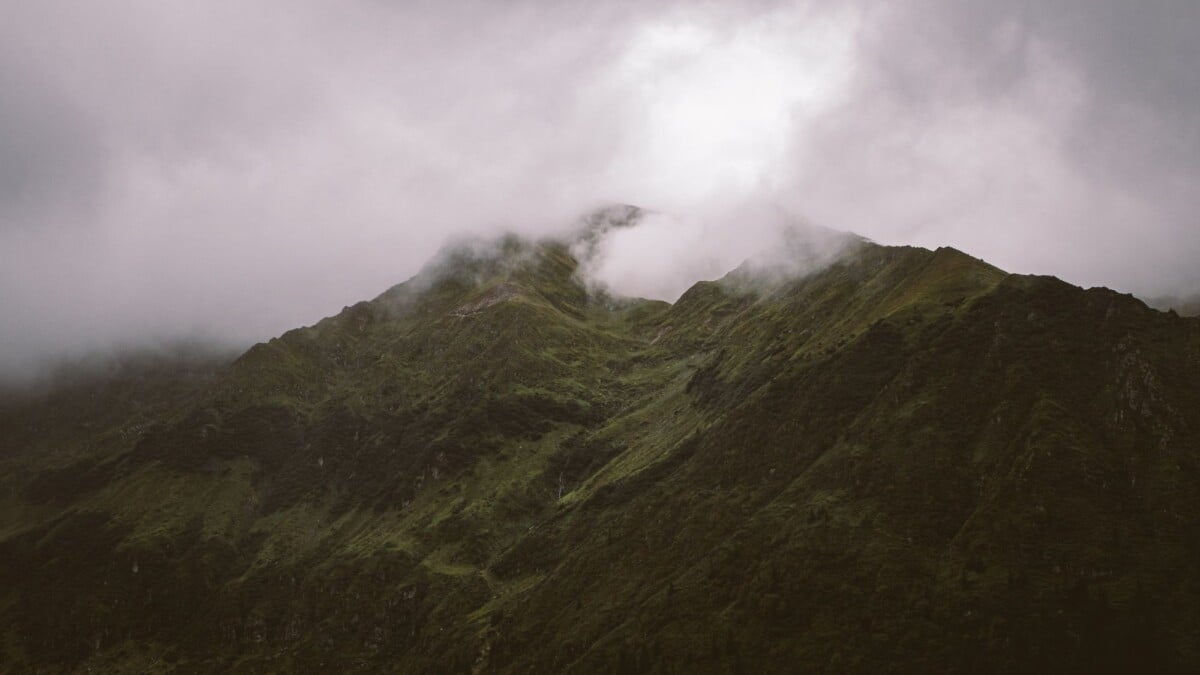 A breathtaking mist-covered mountain peak surrounded by thick clouds.