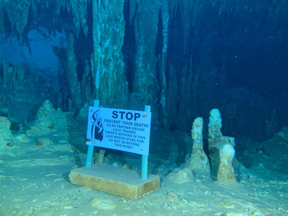 a deep underwater cave with a prominent warning sign urging divers caution | Two Scots Abroad A deep underwater cave with a prominent warning sign urging divers’ caution.