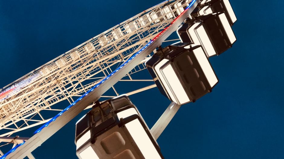 a dramatic low angle view of a brightly lit ferris wheel against a dark night sk | Two Scots Abroad A dramatic low angle view of a brightly lit Ferris wheel against a dark night sky, showcasing its intricate structure.