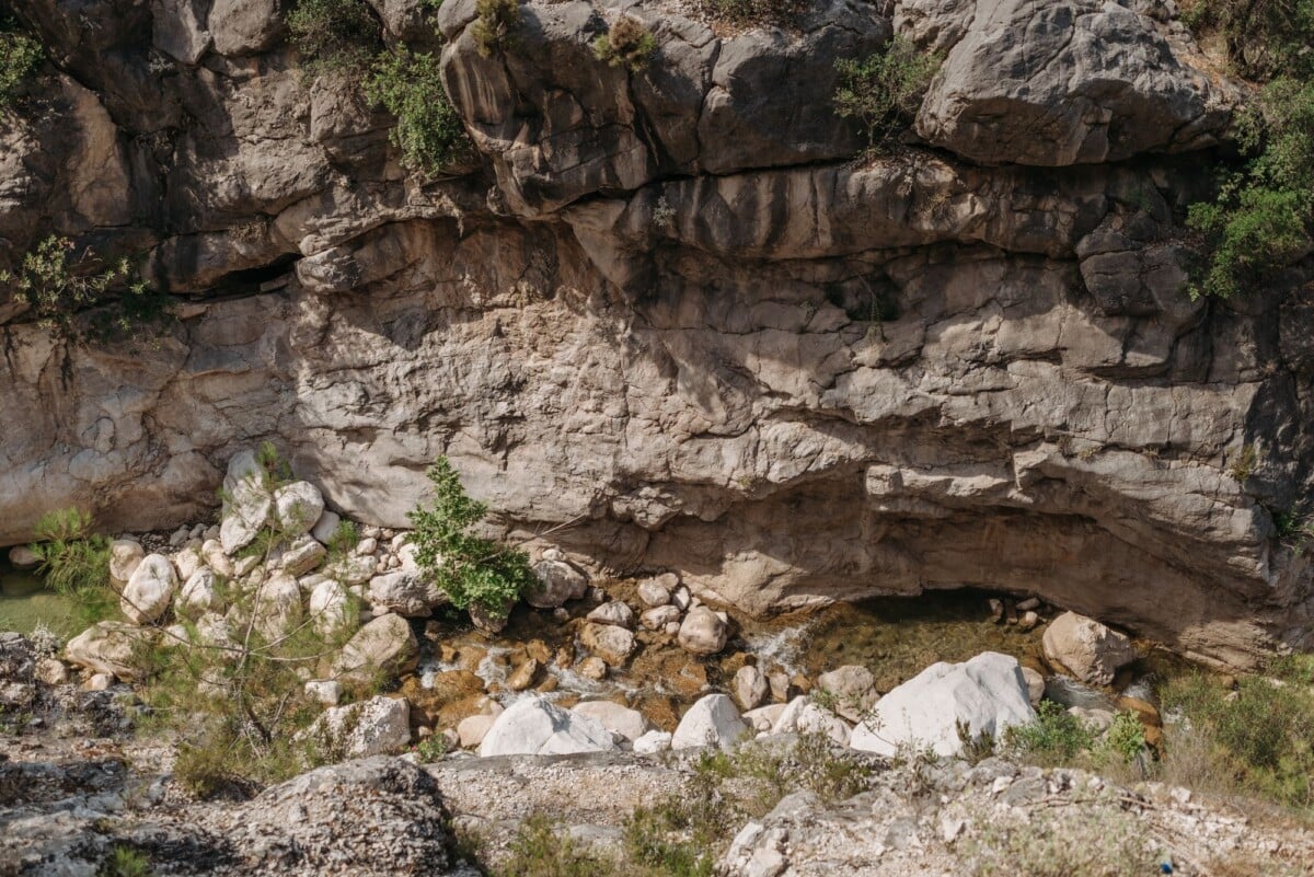 a scenic view of a rocky cliffside with a small stream and natural vegetation | Two Scots Abroad A scenic view of a rocky cliffside with a small stream and natural vegetation.
