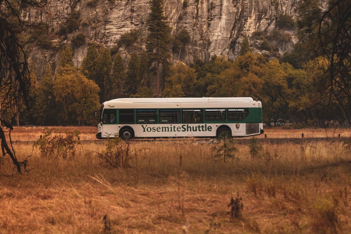 A Yosemite Shuttle bus traveling through scenic Yosemite National Park during autumn.
