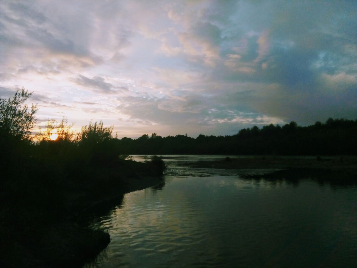 Beautiful sunset view over a calm river in Zarinsk, Russia, reflecting the tranquil nature and peaceful surroundings.