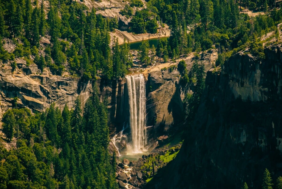 Breathtaking view of a cascading waterfall in Yosemite Valley, surrounded by lush greenery.