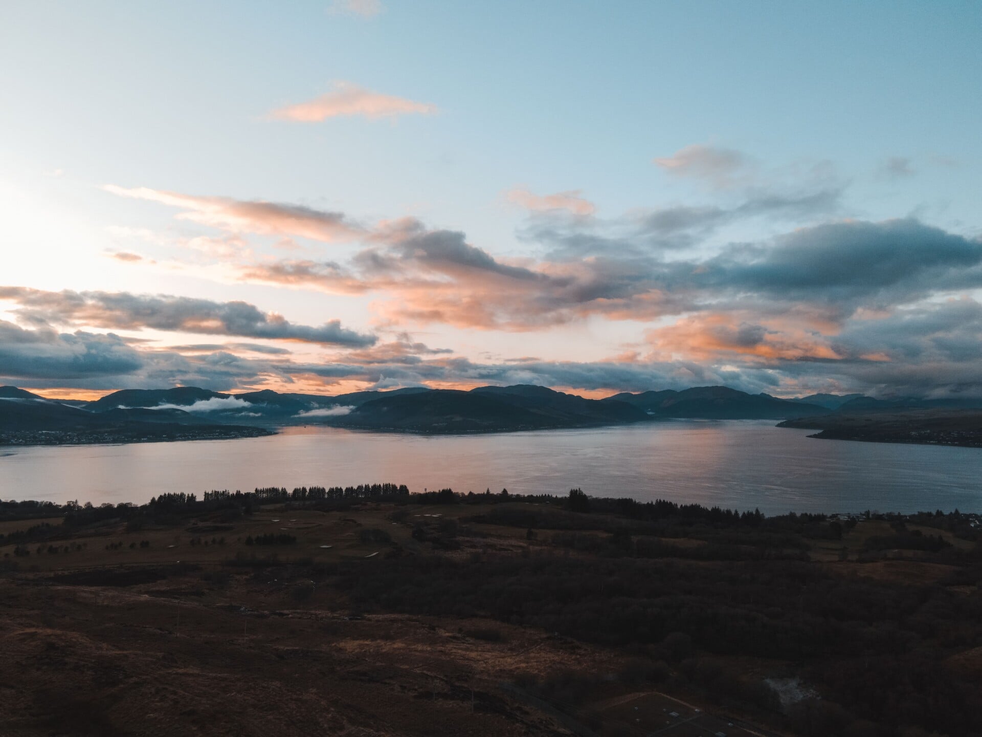 breathtaking view of a serene sunset over a scottish lake with dramatic clouds | Two Scots Abroad Breathtaking view of a serene sunset over a Scottish lake with dramatic clouds.