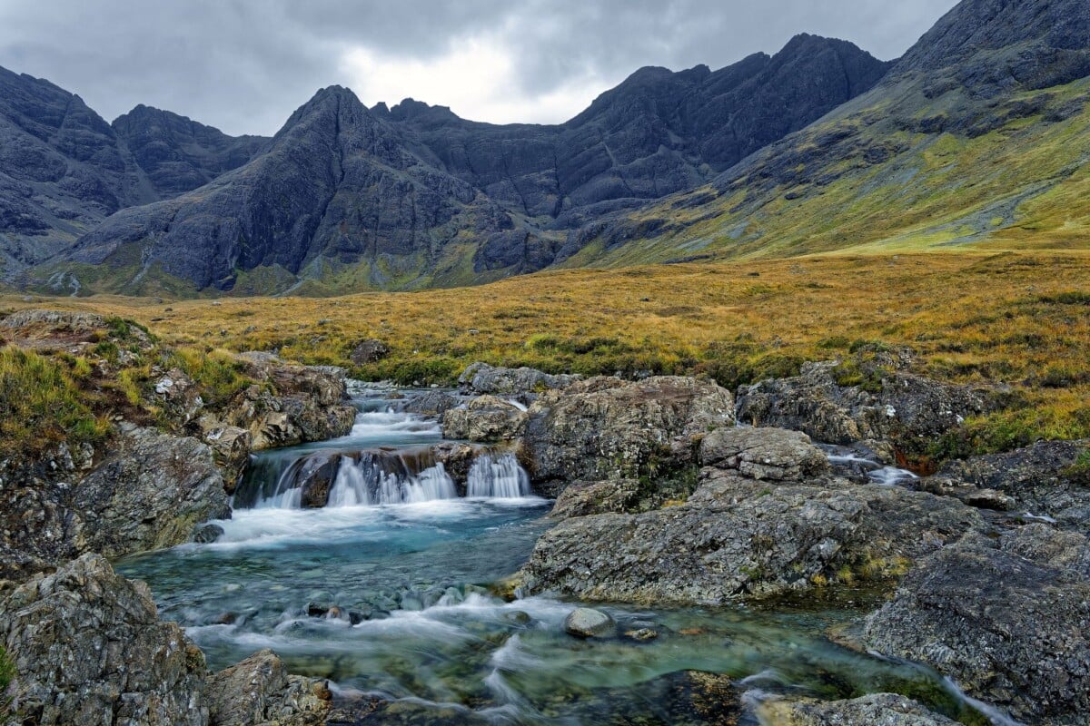 Breathtaking view of a waterfall with rugged mountains in Scotland's Highlands.