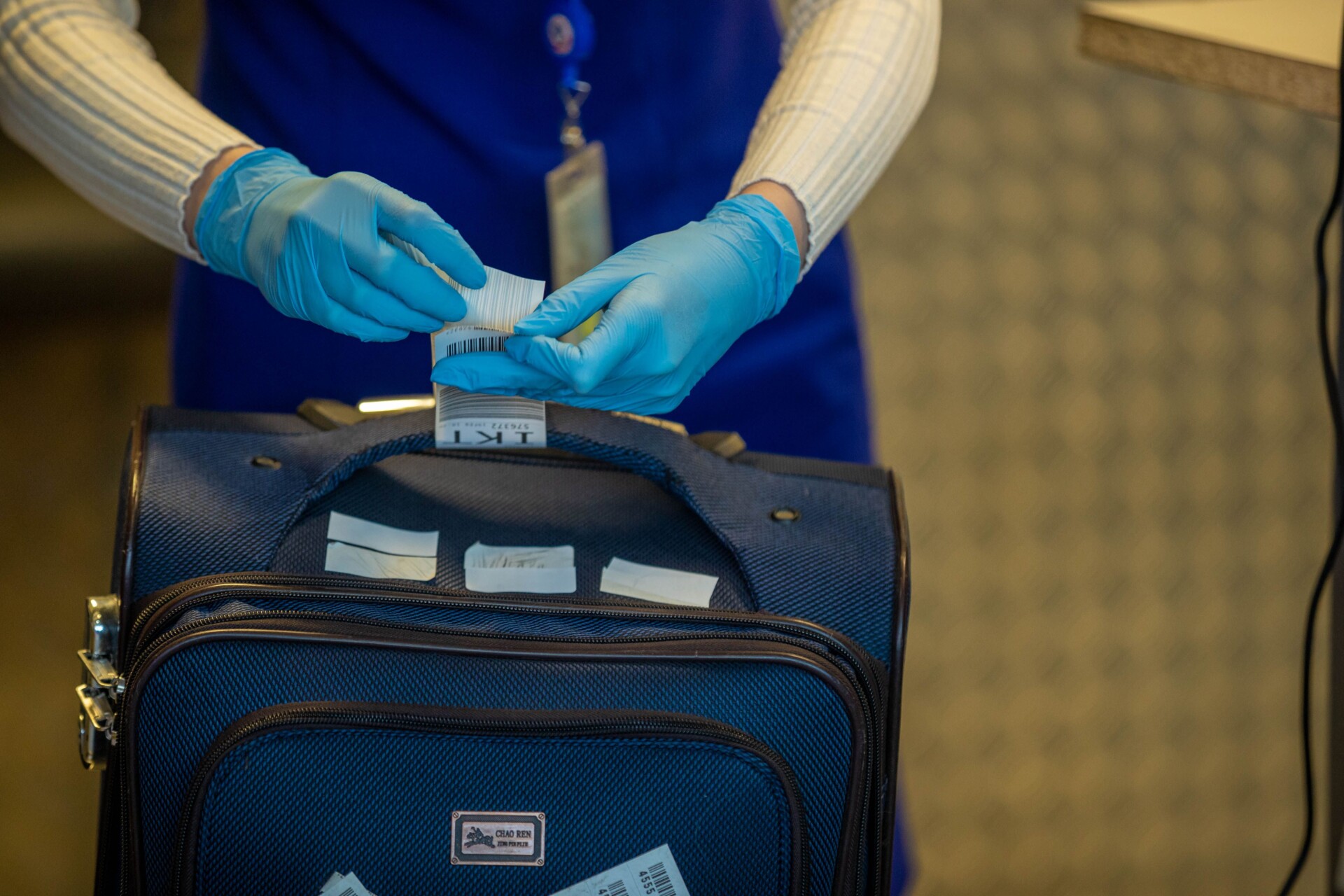 close up of airport security process with gloved hands inspecting luggage tags | Two Scots Abroad Close-up of airport security process with gloved hands inspecting luggage tags.