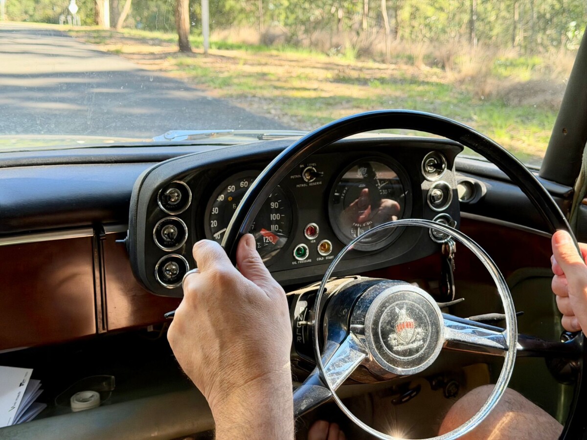 close up of hands on vintage car steering wheel driving down a sunny rural road | Two Scots Abroad Close-up of hands on vintage car steering wheel driving down a sunny rural road.