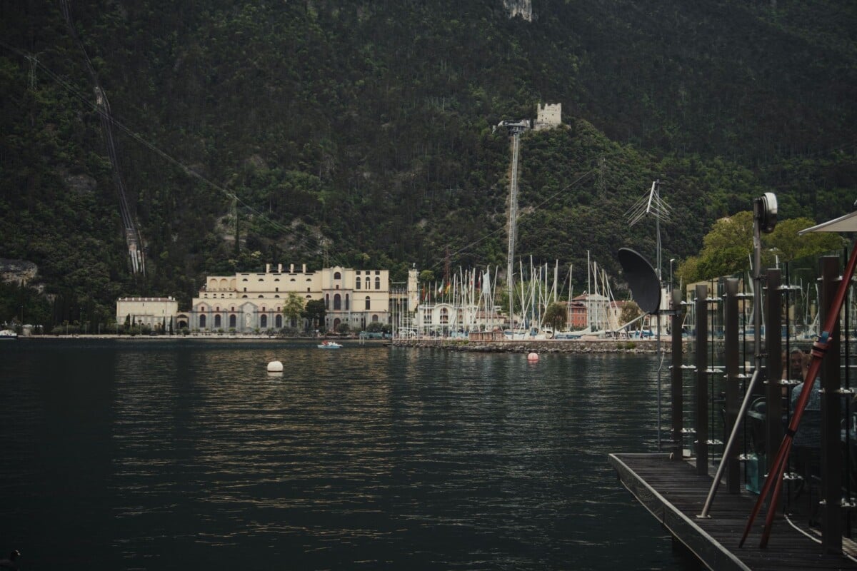 Dramatic view of a historic lakeside building nestled against a forested mountain.